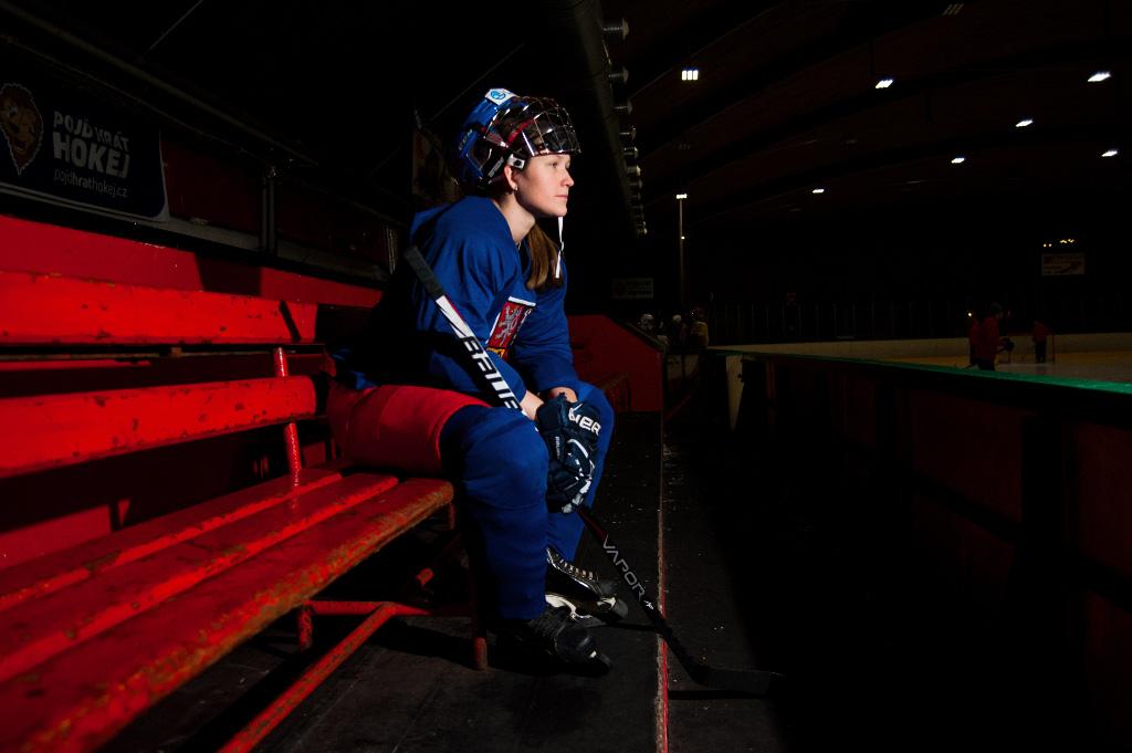 Alena Polenská sedí za hokejovým stadionem a dívá se na led