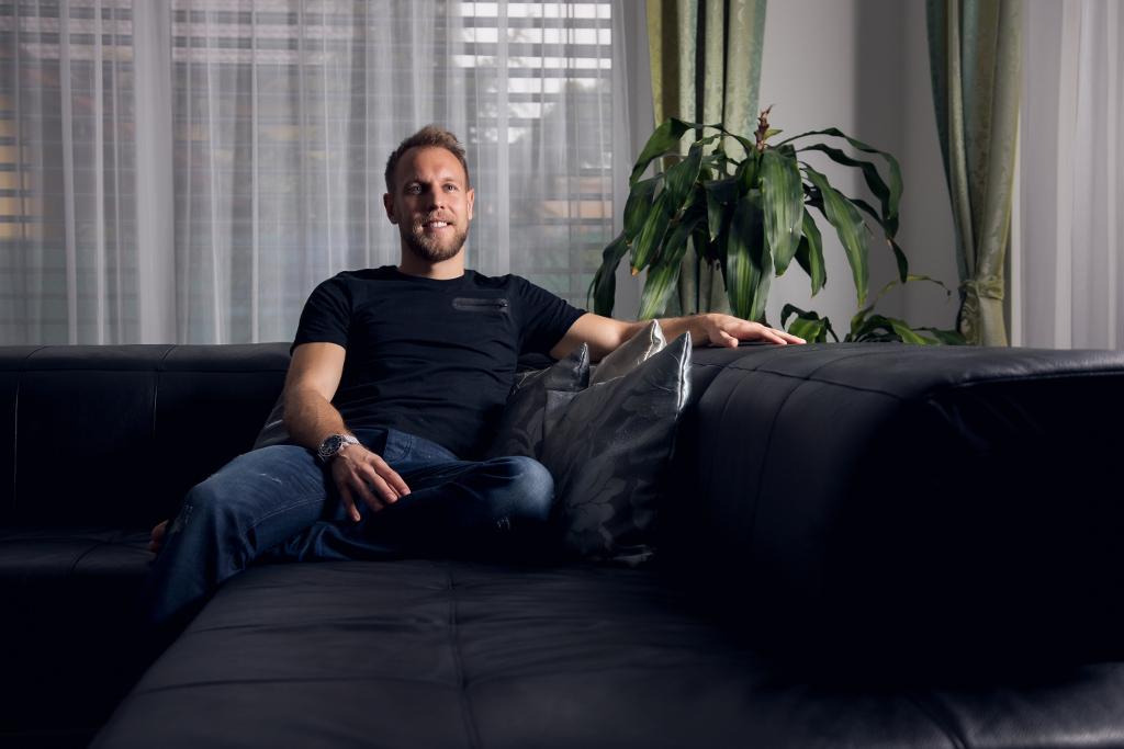 Daniel Kolář sedí na gauči