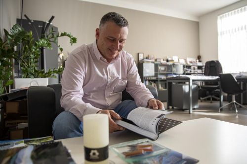 Martin Nohejl sedí v kanceláři, prohlíží si knihu Bez Frází a usmívá se